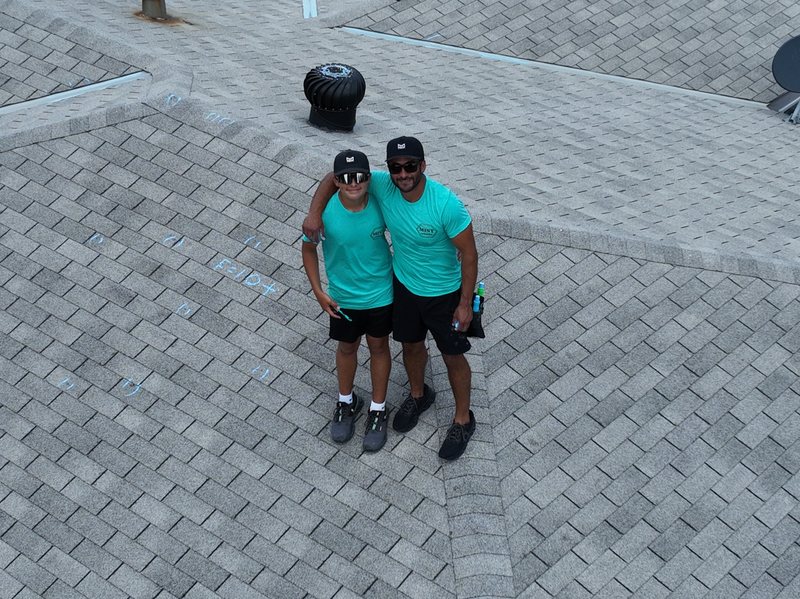 Two Mint Exteriors crew standing on the roof surrounded by blue chalk marks left by the inspection